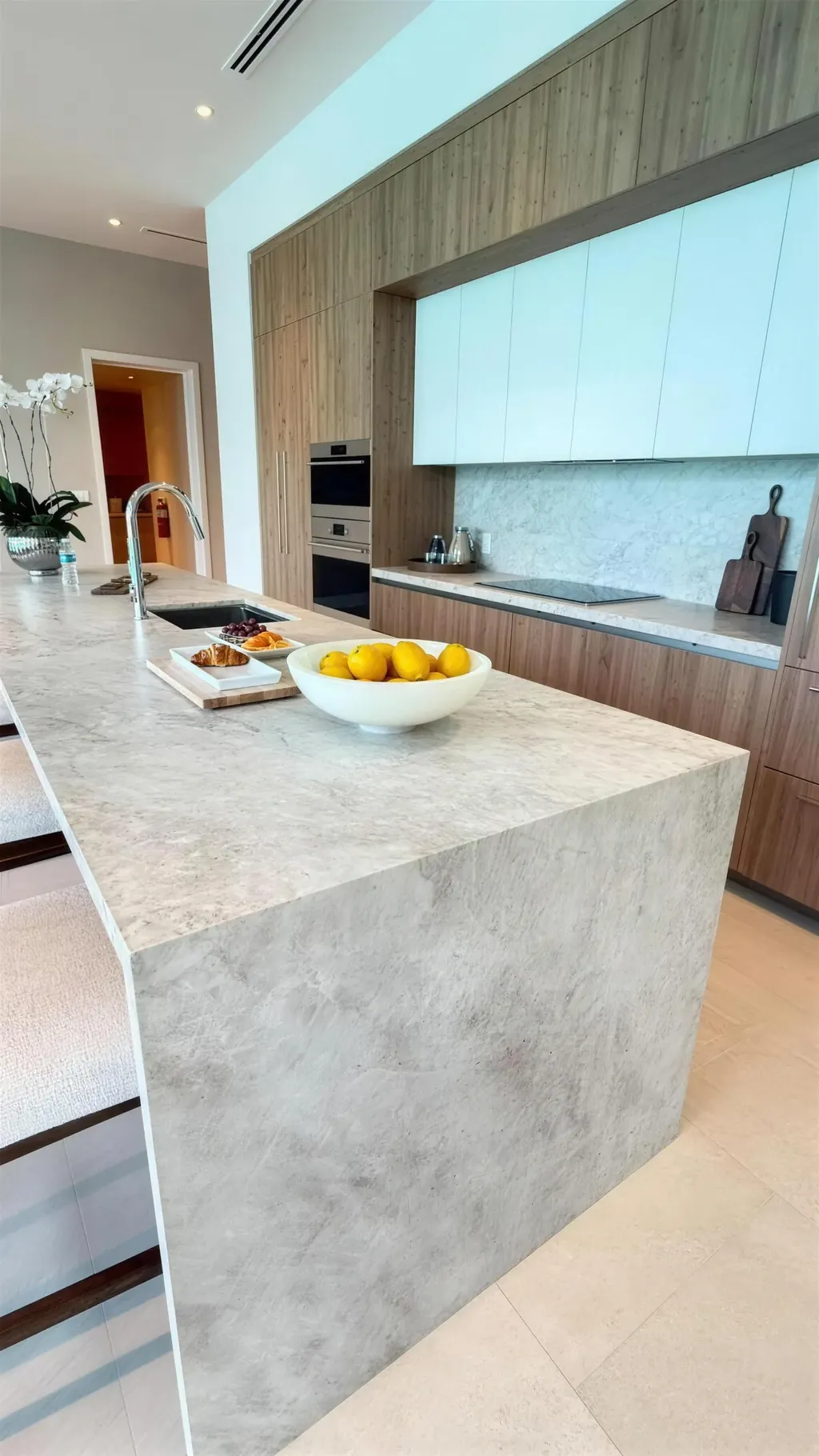 Cozinha com ilha em pedra e eletrodomésticos integrados, em formato vertical
